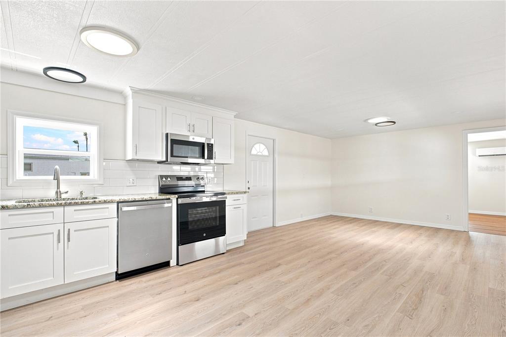 A kitchen with white cabinets, stainless steel appliances, and light wood-look flooring — 6711 CLEMENS BOULEVARD, PORT RICHEY, FL