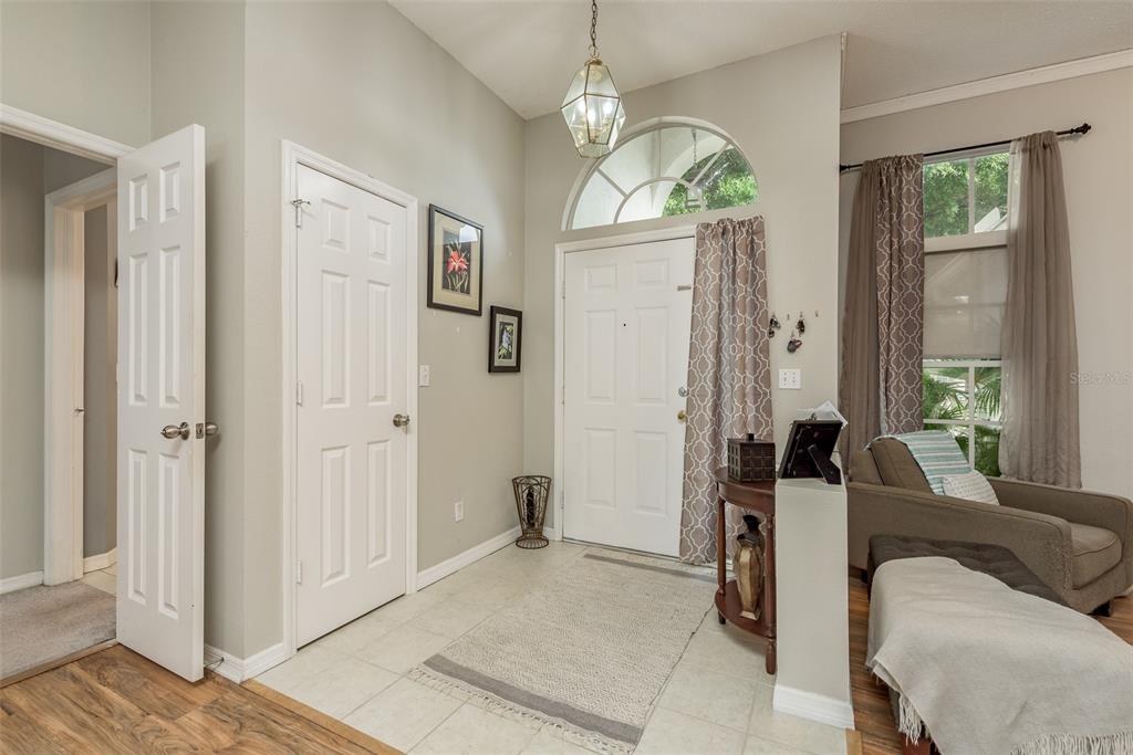A tiled entryway features a white front door, a pendant light, and an adjacent living area — 28739 COTTAGEWOOD DRIVE, WESLEY CHAPEL, FL
