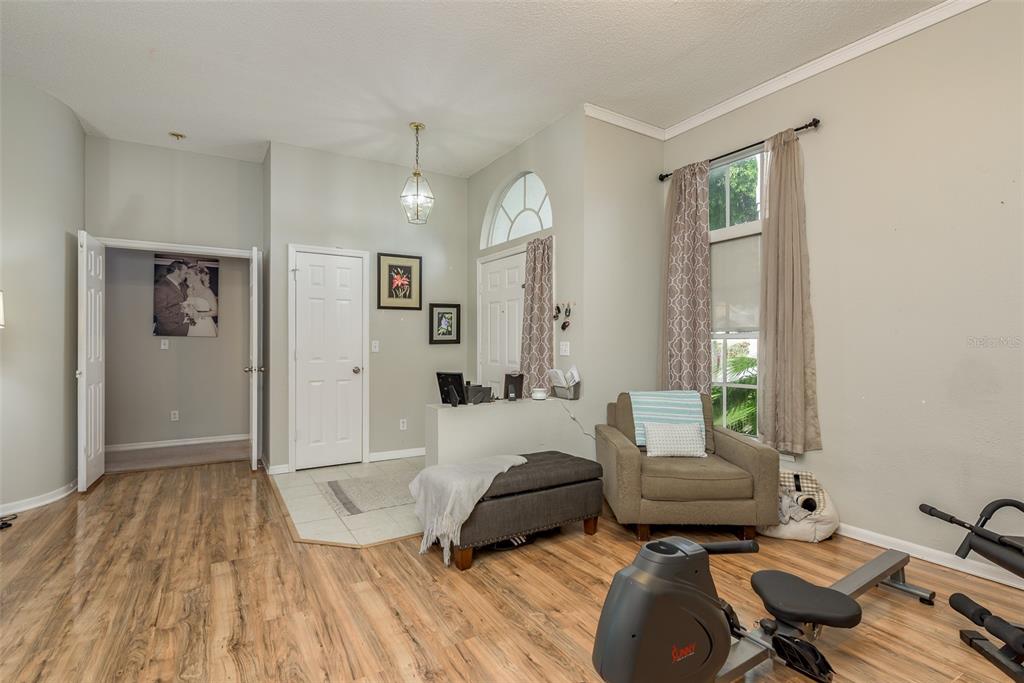 A living area features wood-look flooring, a gray armchair, a storage ottoman, and exercise equipment — 28739 COTTAGEWOOD DRIVE, WESLEY CHAPEL, FL