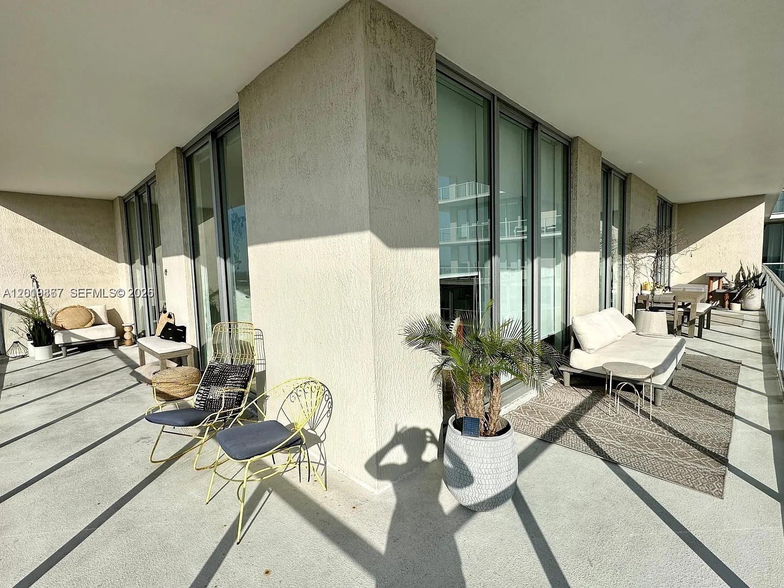 A spacious outdoor balcony features modern furniture, potted plants, and large sliding glass doors — 3470 E Coast Ave # H1805, Miami FL 33137, MIAMI, FL