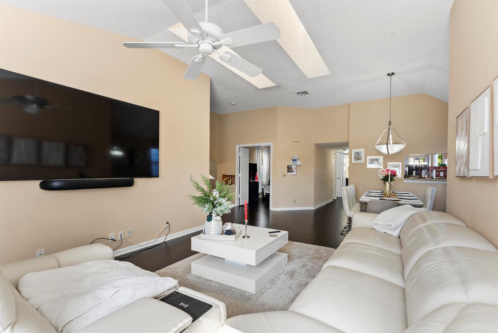 A living room features a white sectional sofa, a coffee table, and a wall-mounted television — 5359 Buckhead Circle # 2031, Boca Raton FL 33486, BOCA RATON, FL