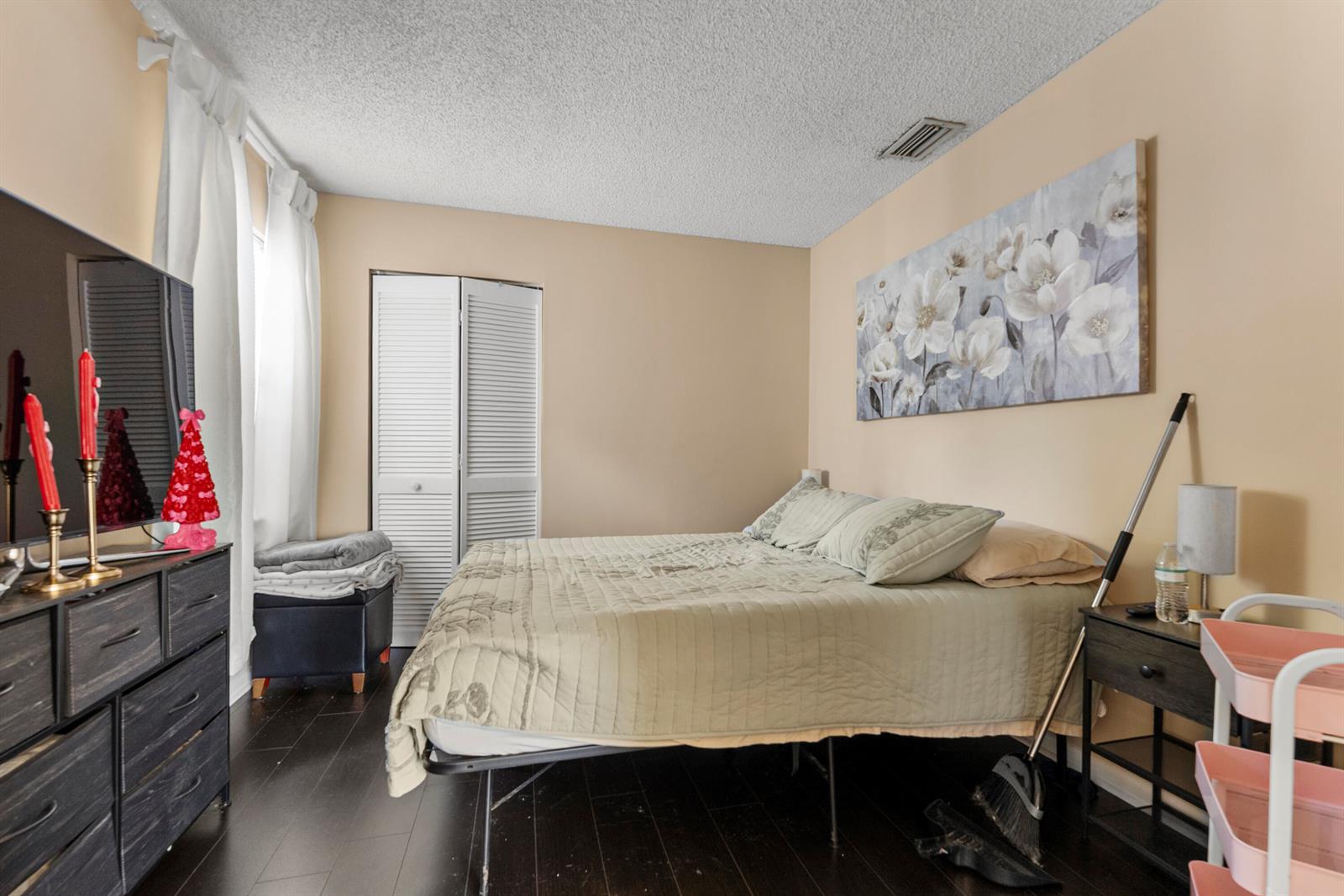 A bedroom features a bed with a green quilt, a dresser, and a floral wall painting — 5359 Buckhead Circle # 2031, Boca Raton FL 33486, BOCA RATON, FL
