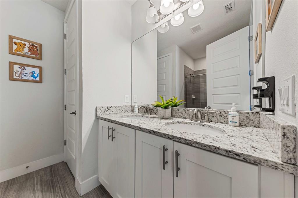 A bathroom features a double-sink vanity with granite countertops, white cabinets, and a large mirror — 451 LASSO DRIVE, KISSIMMEE, FL