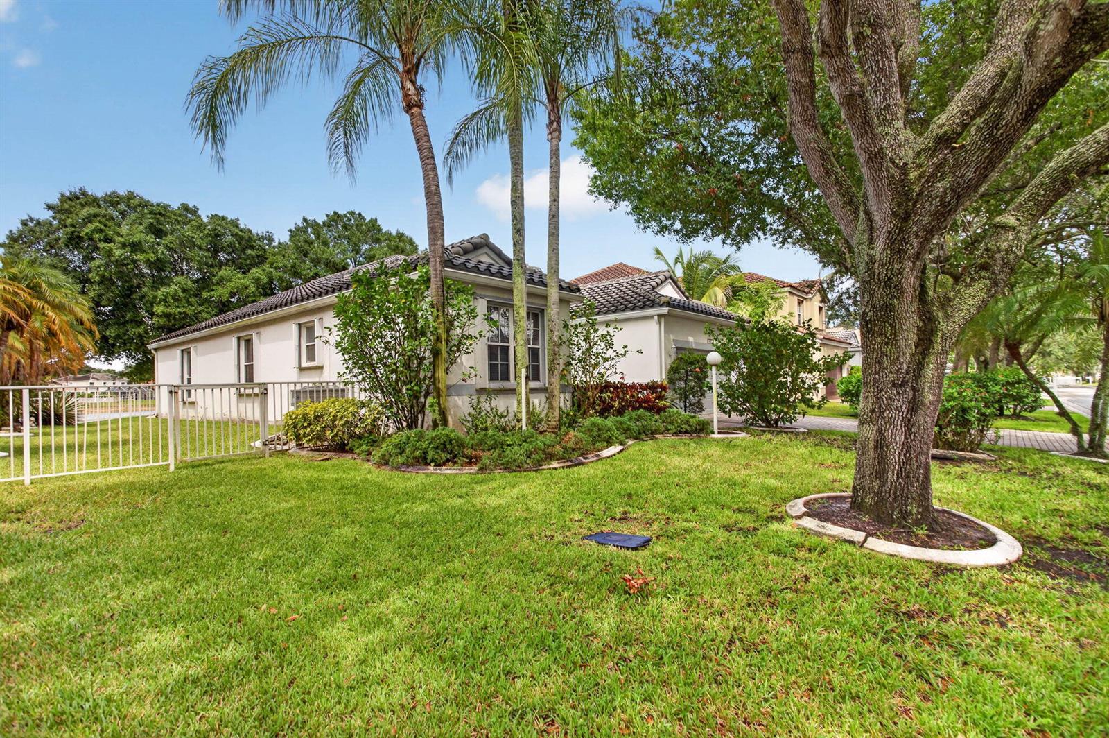 A single-story house with a tiled roof, palm trees, and a large tree in the yard — 6621 NW 78th Drive, Parkland FL 33067, PARKLAND, FL