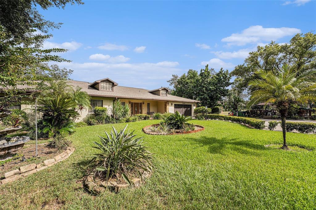 A single-story house with a tan exterior, dormer windows, and a landscaped front lawn — 5105 N 45TH STREET, TAMPA, FL