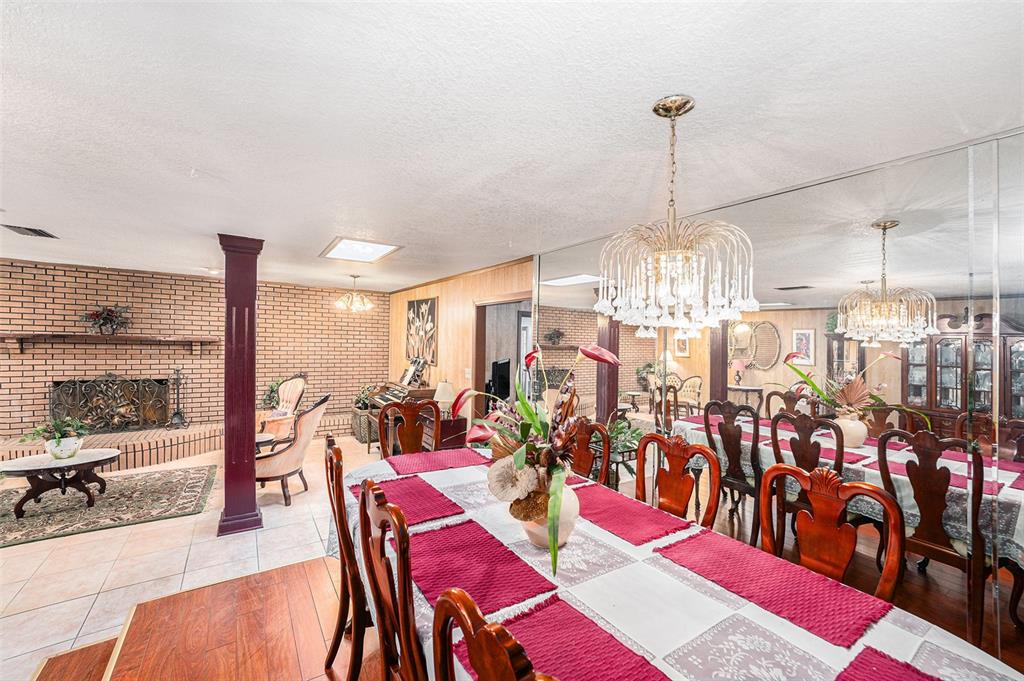 A dining room with a chandelier, mirrored wall, and an adjacent brick fireplace area — 5105 N 45TH STREET, TAMPA, FL