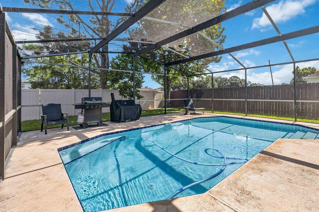 A screened-in backyard patio features a swimming pool, a grill, and a fenced perimeter — 664 MADRID DRIVE, KISSIMMEE, FL