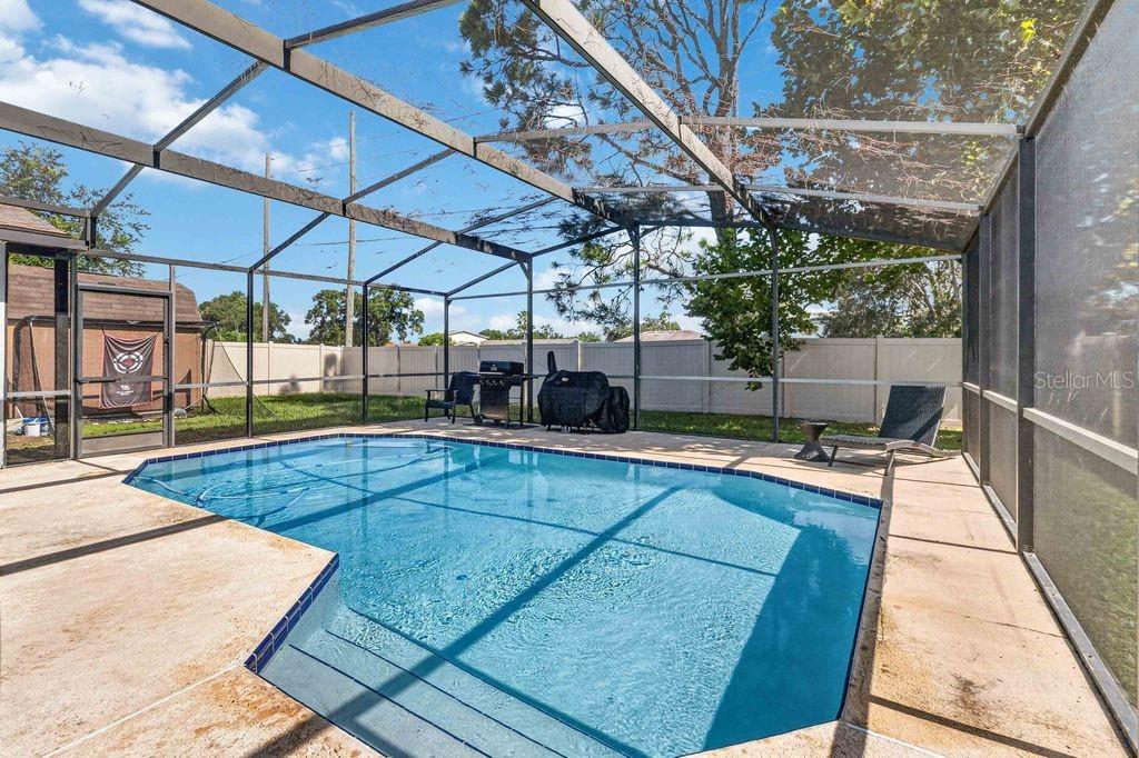 A screened-in patio features a rectangular swimming pool with steps and a backyard fence — 664 MADRID DRIVE, KISSIMMEE, FL