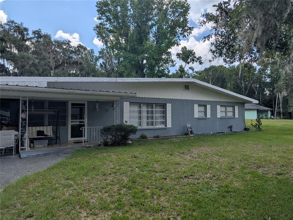 A single-story gray house with a metal roof and a covered front porch — 7633 S CRESCENT LOOP, FLORAL CITY, FL