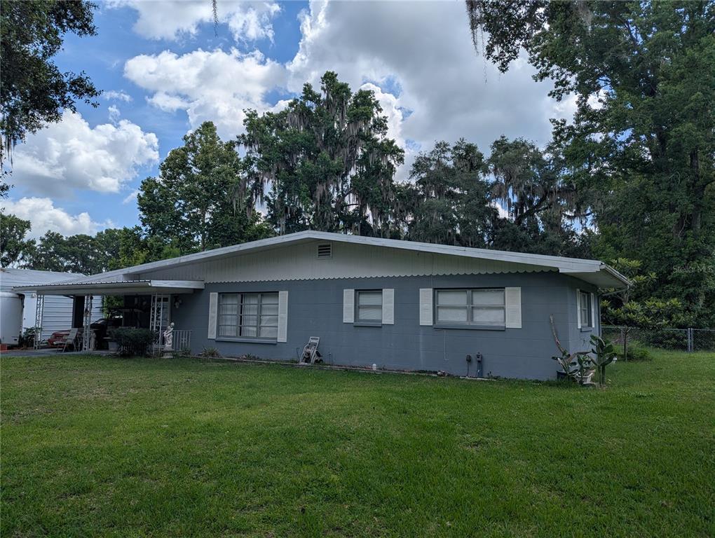 A single-story gray house with a carport and a large front lawn — 7633 S CRESCENT LOOP, FLORAL CITY, FL