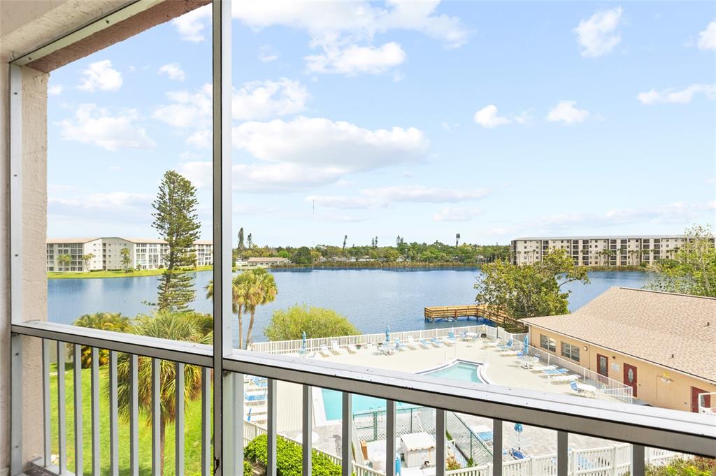 A screened balcony overlooks a lake, a swimming pool, and surrounding apartment buildings — 3959 LAKE BAYSHORE DRIVE UNIT F 412, BRADENTON, FL
