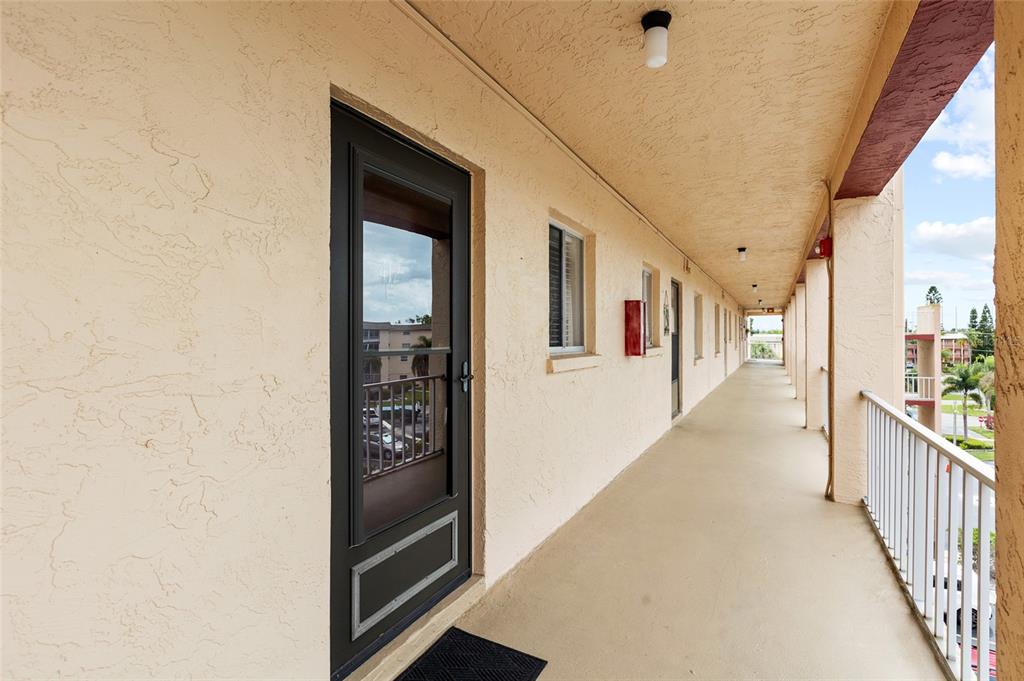 An outdoor apartment building walkway with a black storm door and white metal railings — 3959 LAKE BAYSHORE DRIVE UNIT F 412, BRADENTON, FL