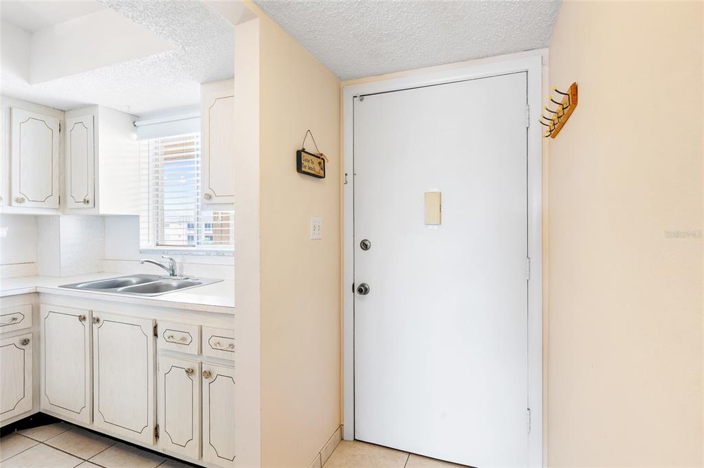 A white door stands next to a kitchen with white cabinets and a window — 3959 LAKE BAYSHORE DRIVE UNIT F 412, BRADENTON, FL