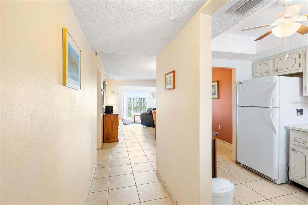 A tiled hallway leads from a kitchen with a white refrigerator toward a living area — 3959 LAKE BAYSHORE DRIVE UNIT F 412, BRADENTON, FL
