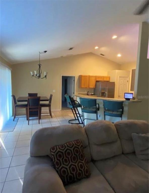 A living room with a dining area and kitchen breakfast bar featuring tile flooring — 8040 SW 128TH LOOP, OCALA, FL