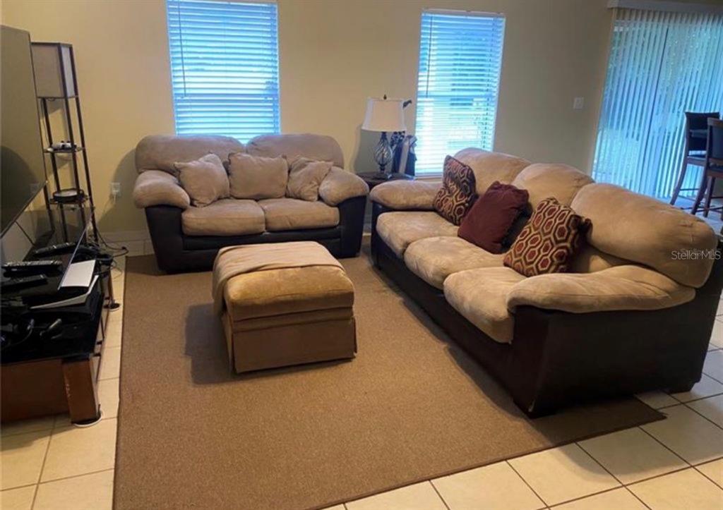 A kitchen with wood cabinets, stainless steel appliances, and tile flooring opens to a dining area — 8040 SW 128TH LOOP, OCALA, FL