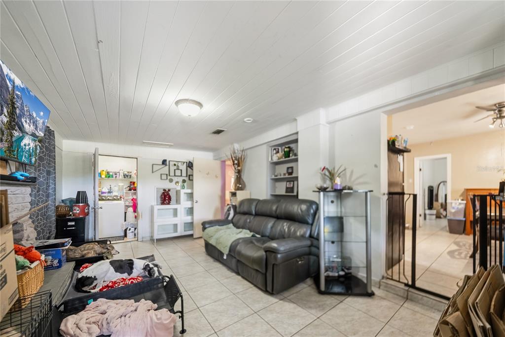 A living room features tile flooring, a white plank ceiling, and a gray leather sofa — 761 SEMINOLA BOULEVARD, CASSELBERRY, FL