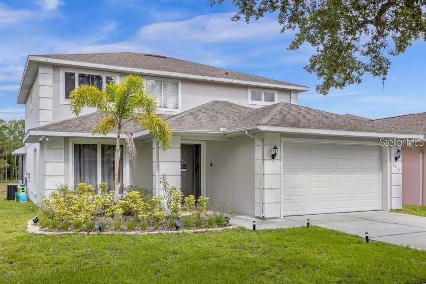 A two-story house with a white stucco exterior, a palm tree, and a two-car garage — 2912 SUNSET LAKES BOULEVARD, KISSIMMEE, FL