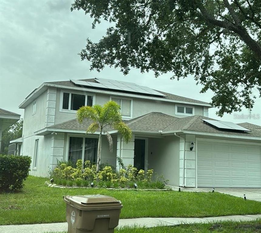 A two-story house with a light-colored exterior, solar panels on the roof, and a garage — 2912 SUNSET LAKES BOULEVARD, KISSIMMEE, FL
