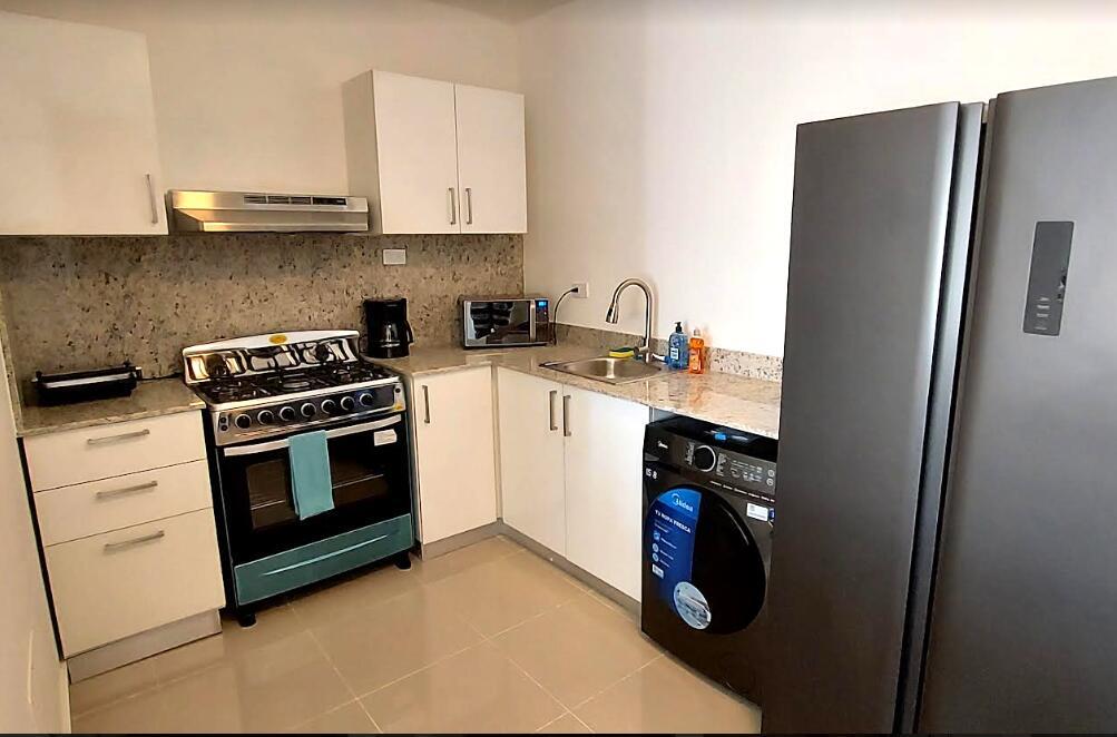 A kitchen features white cabinets, granite countertops, a gas stove, and a built-in washing machine — Calle 6 Calle 6, Punta Del Este 2 # C301, FL
