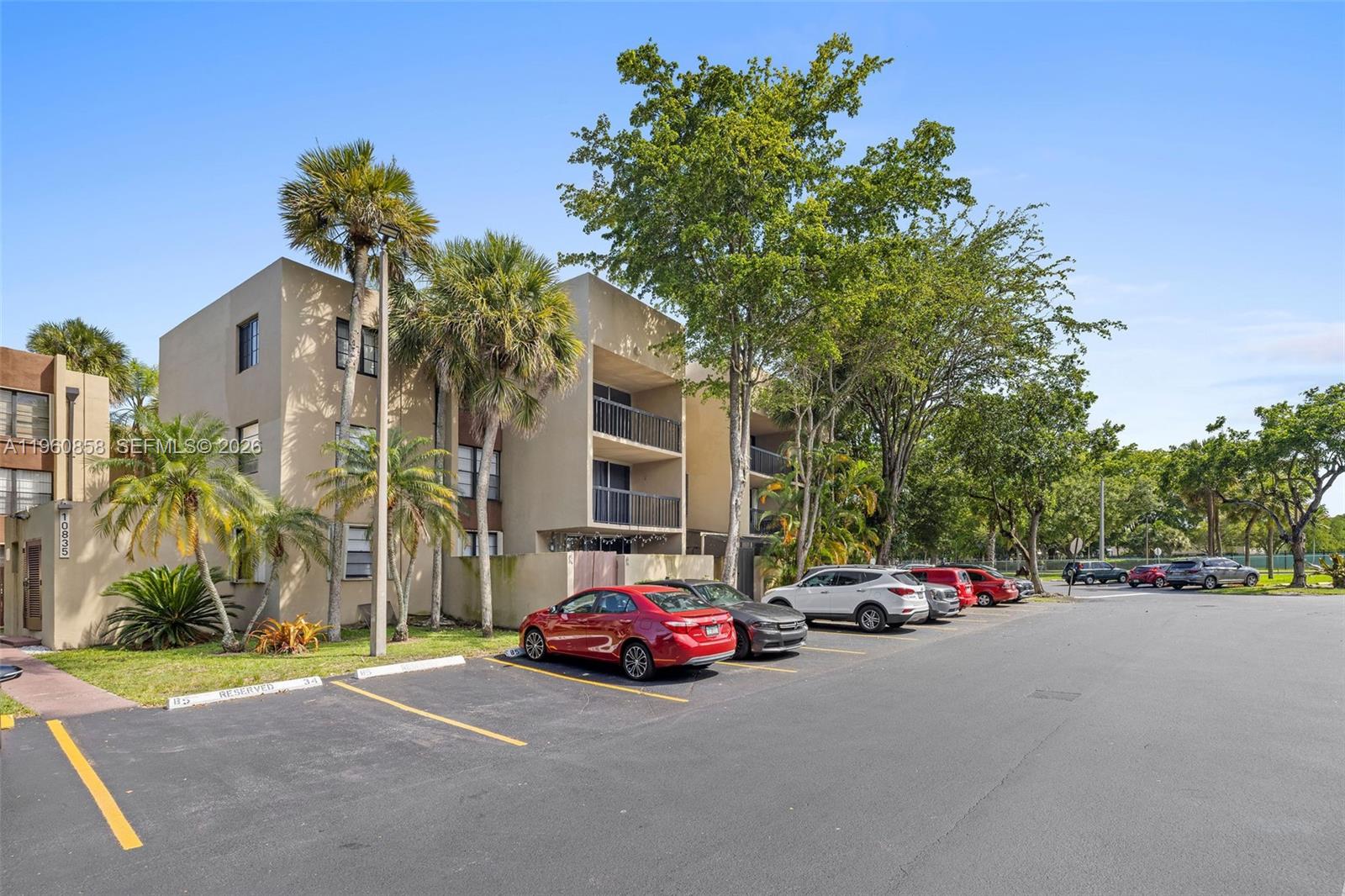 A multi-story apartment building with a parking lot in front and several palm trees — 10835 SW 112th Ave # 305, Miami FL 33176, MIAMI, FL