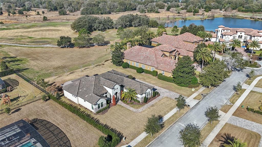 An aerial view shows two large residential houses with tiled roofs situated near a lake — 25620 GRANDVIEW POINTE, SORRENTO, FL