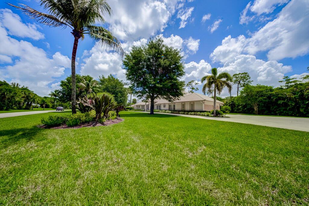 A large house with a tile roof sits behind a green lawn and palm trees — 13406 Doubletree Circle, Wellington FL 33414, WELLINGTON, FL