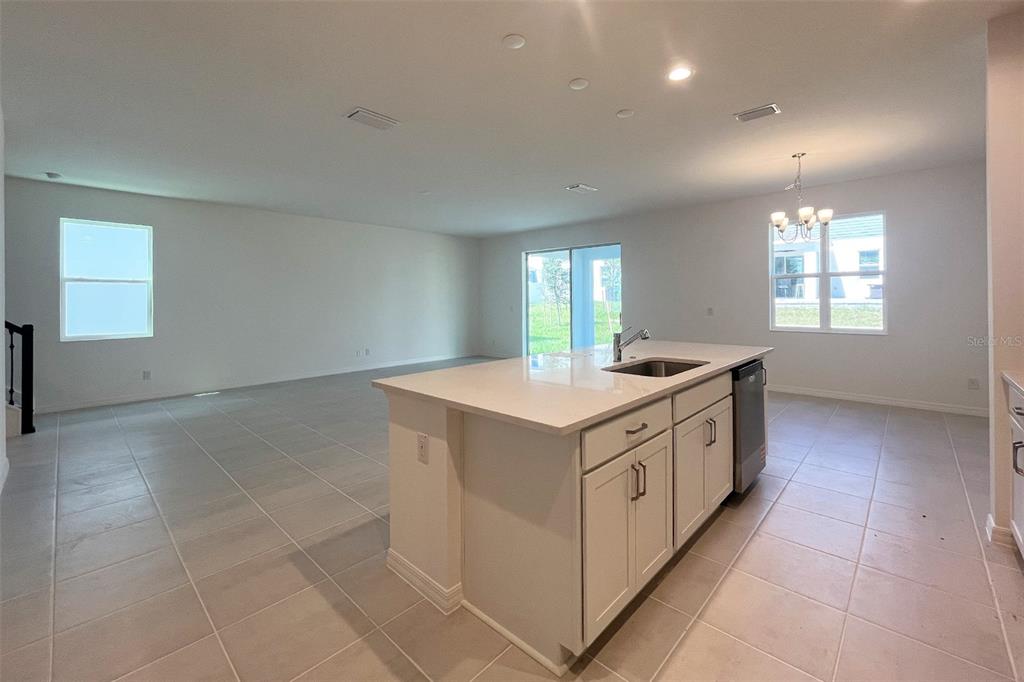 A kitchen island with a sink and white cabinets sits in an open-concept living area — 7036 ROLLING LEAF ROAD, GROVELAND, FL
