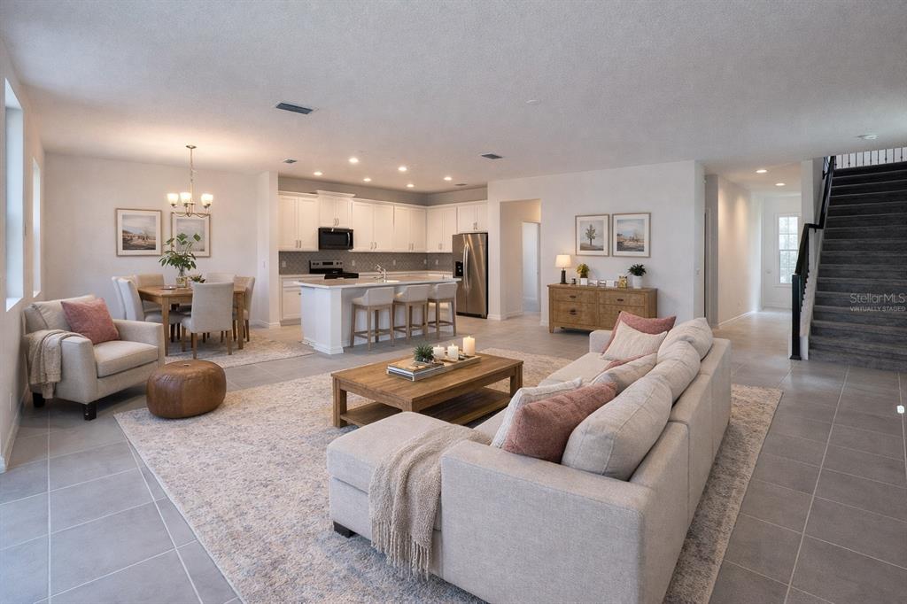 An open-concept living room, dining area, and kitchen with white cabinetry and a staircase — 7036 ROLLING LEAF ROAD, GROVELAND, FL