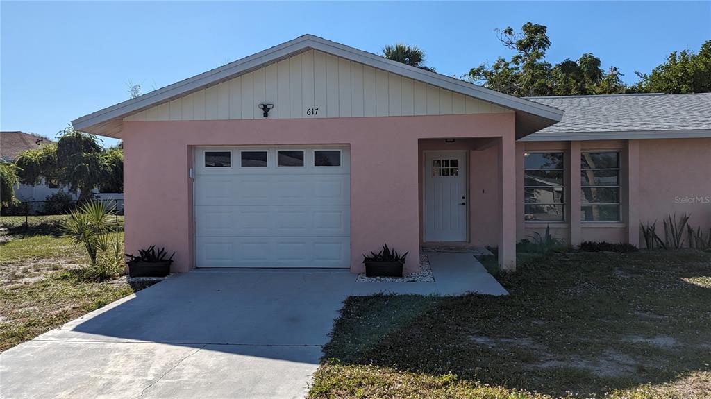A single-story house with pink stucco walls, a white garage door, and a front entrance — 617 INDIANA AVENUE, NOKOMIS, FL