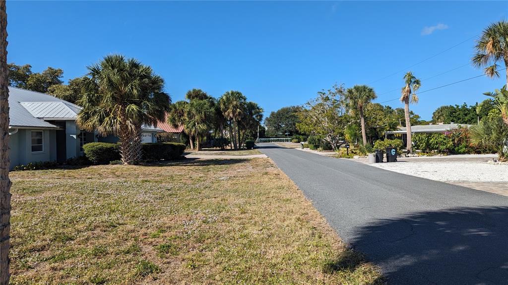 A paved street runs through a residential neighborhood with palm trees and houses — 617 INDIANA AVENUE, NOKOMIS, FL