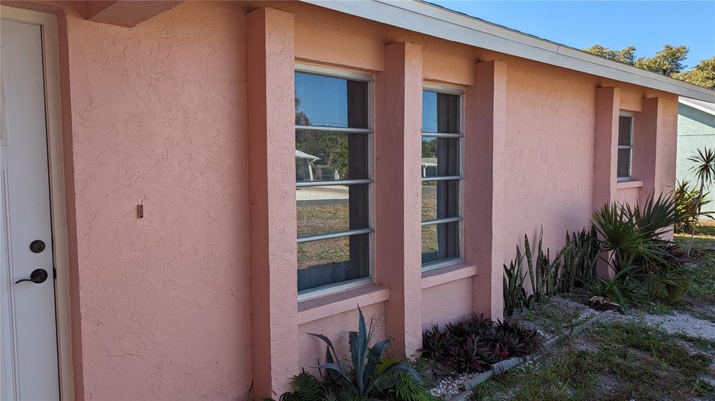 The exterior of a pink stucco house features vertical pillars between windows and a white door — 617 INDIANA AVENUE, NOKOMIS, FL