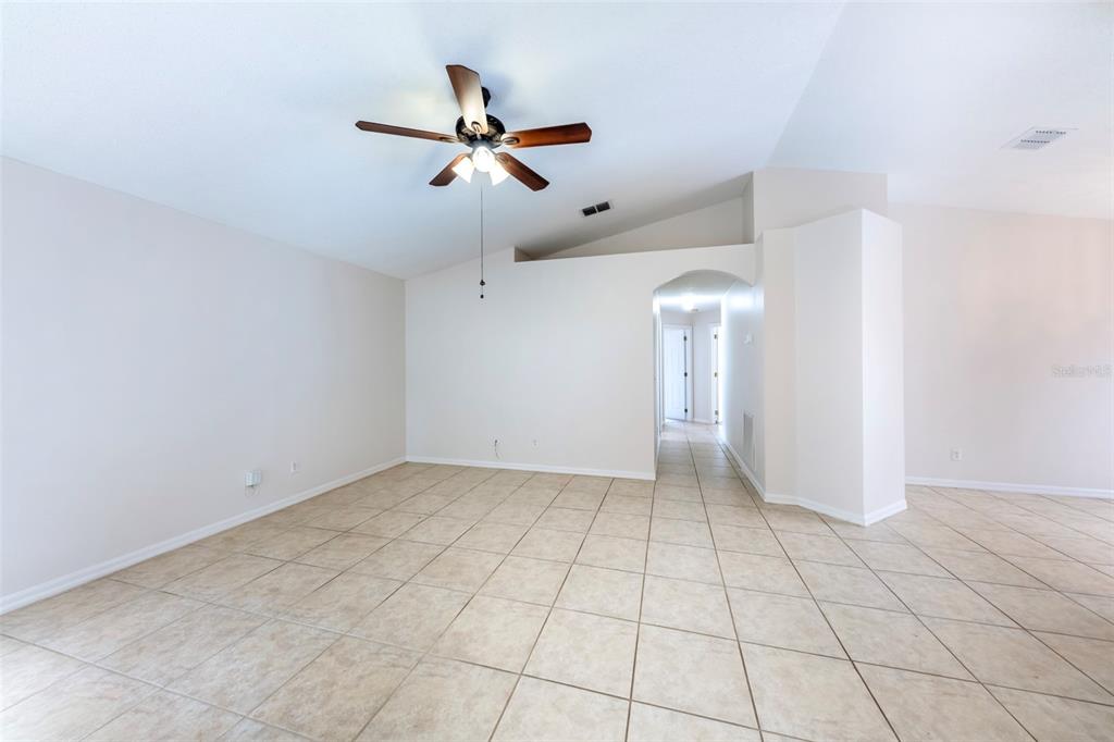 An empty room with beige tile flooring, a vaulted ceiling, and a ceiling fan — 10109 VISTA COVE LANE, ORLANDO, FL