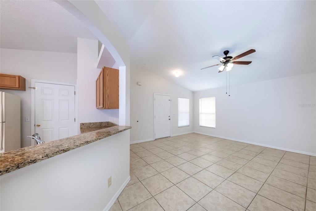 An open-concept living area features light tile flooring, a ceiling fan, and a granite countertop — 10109 VISTA COVE LANE, ORLANDO, FL