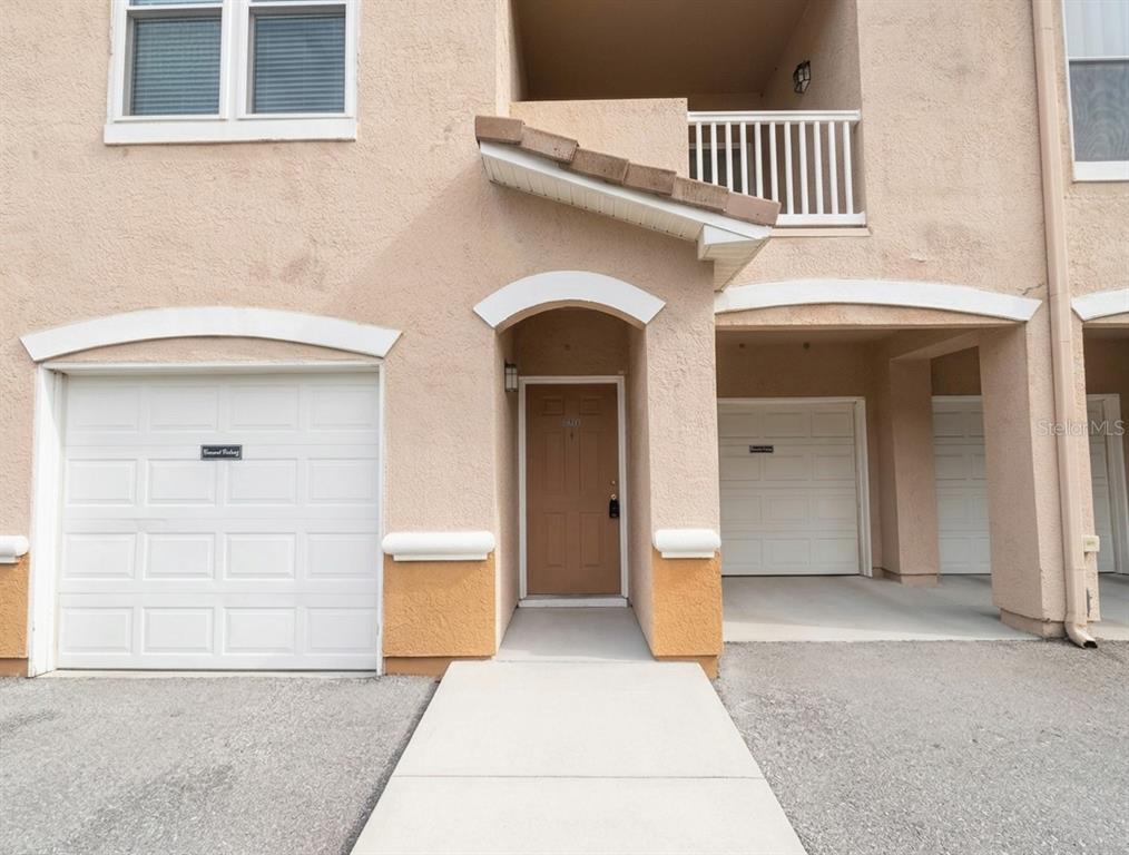 The exterior of a multi-story townhouse features a brown front door, a garage, and a balcony — 10412 VILLA VIEW CIRCLE UNIT 10412, TAMPA, FL