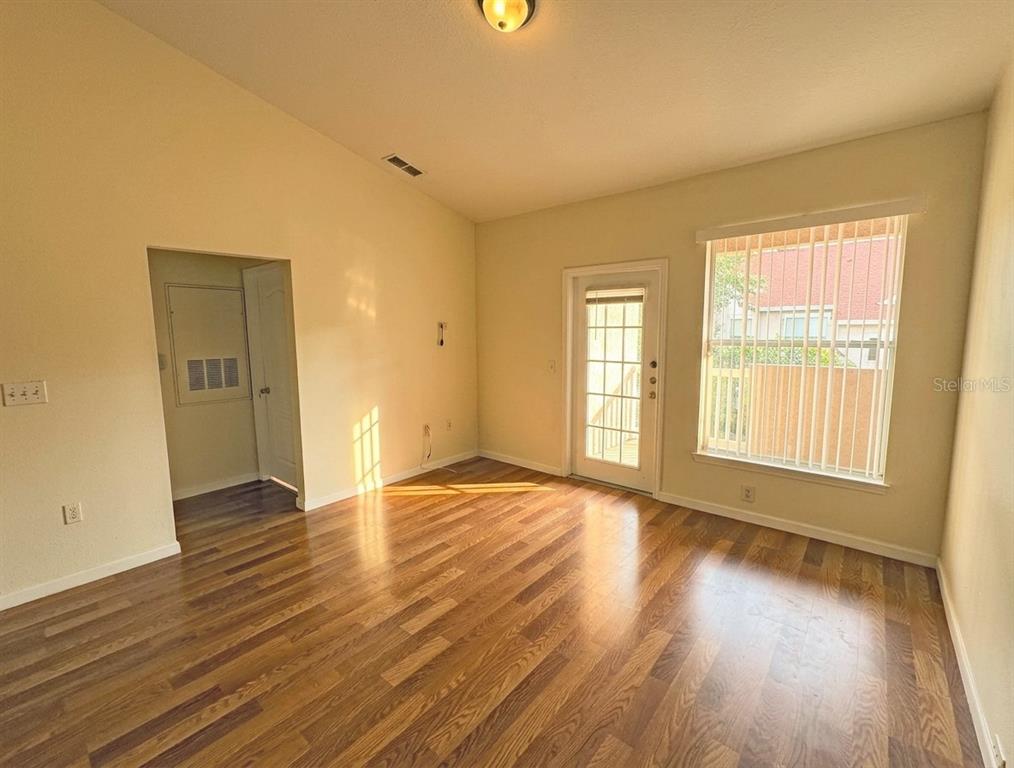 An empty room features wood-look flooring, a glass-paneled door, and a window with blinds — 10412 VILLA VIEW CIRCLE UNIT 10412, TAMPA, FL