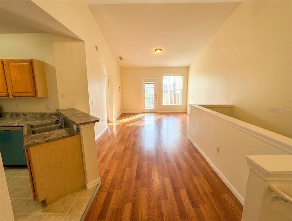 An open-concept living area features wood-look flooring, a kitchen with granite countertops, and a balcony — 10412 VILLA VIEW CIRCLE UNIT 10412, TAMPA, FL