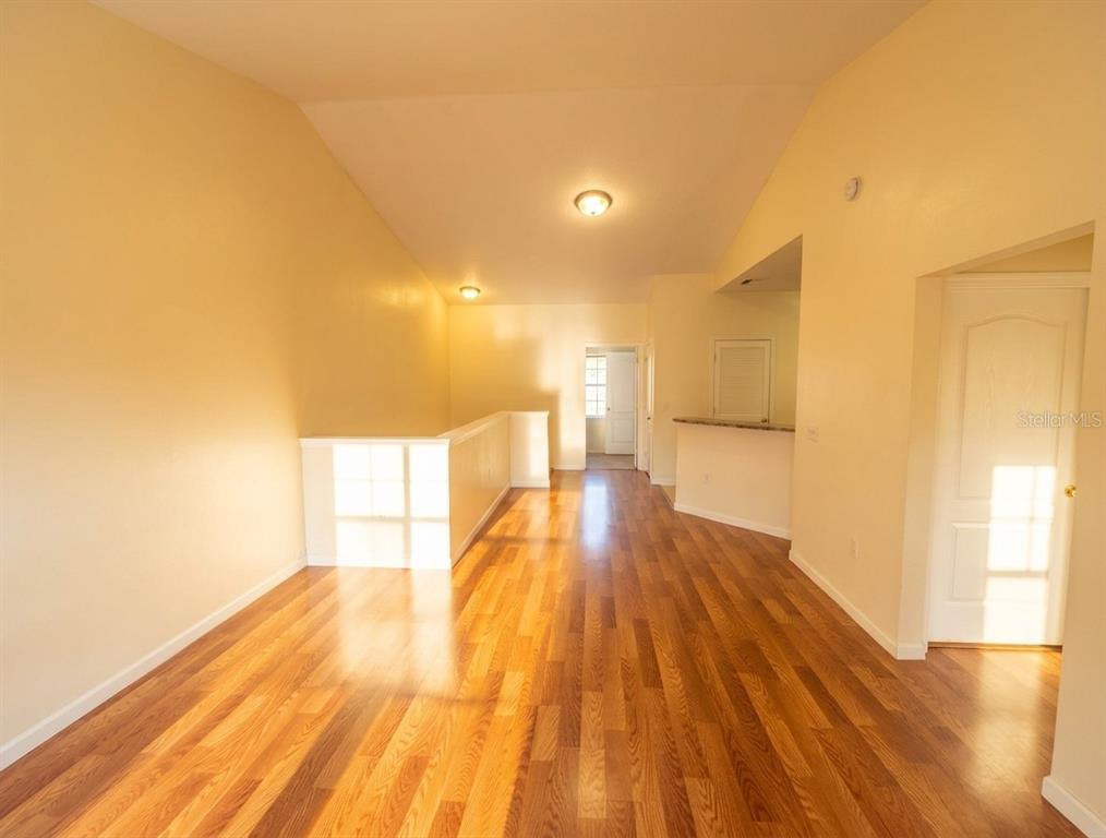 An interior view of a living area featuring hardwood floors and a white half-wall — 10412 VILLA VIEW CIRCLE UNIT 10412, TAMPA, FL