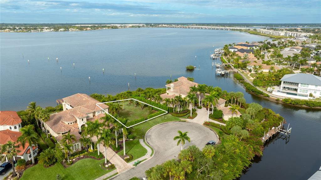 An aerial view shows a vacant waterfront lot situated between two large residential homes — 4223 HAWK ISLAND DRIVE, BRADENTON, FL