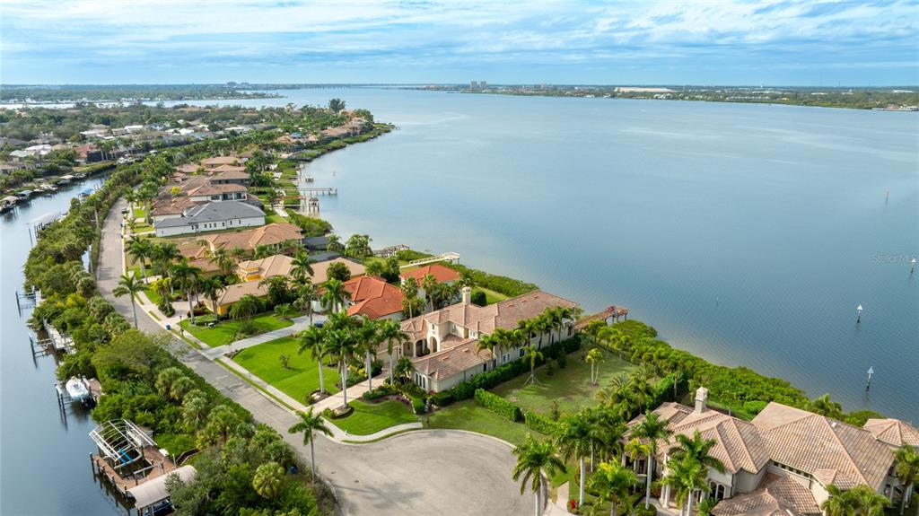 An aerial view shows luxury waterfront homes with tile roofs along a coastal inlet — 4223 HAWK ISLAND DRIVE, BRADENTON, FL