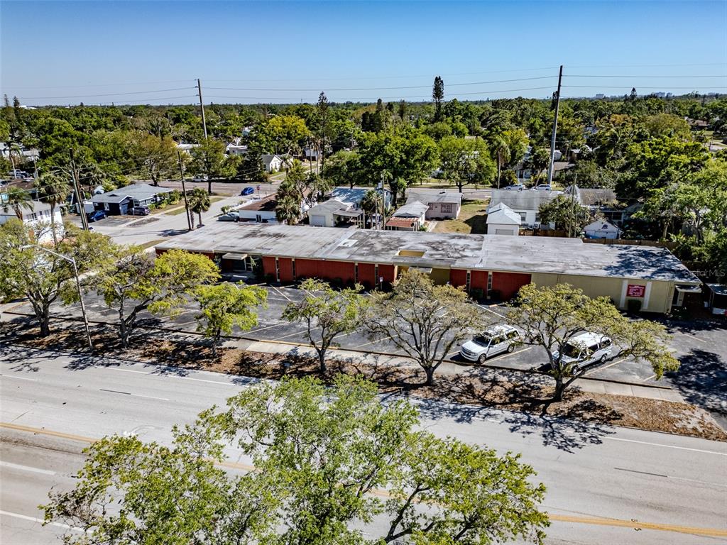 An aerial view shows a long, flat-roofed commercial building with a parking lot and trees — 4200 CENTRAL AVENUE S, ST PETERSBURG, FL