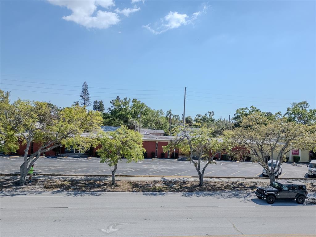 A low-slung, red commercial building sits behind a parking lot with several trees — 4200 CENTRAL AVENUE S, ST PETERSBURG, FL