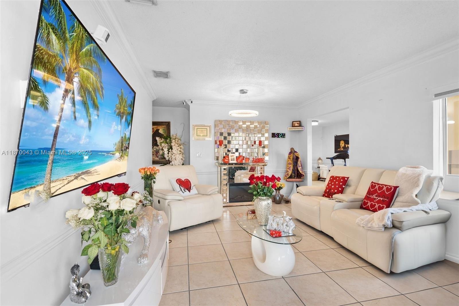 A living room features white leather sofas, a wall-mounted television, and a mirrored fireplace — 17874 SW 114th Ave, Miami FL 33157, MIAMI, FL