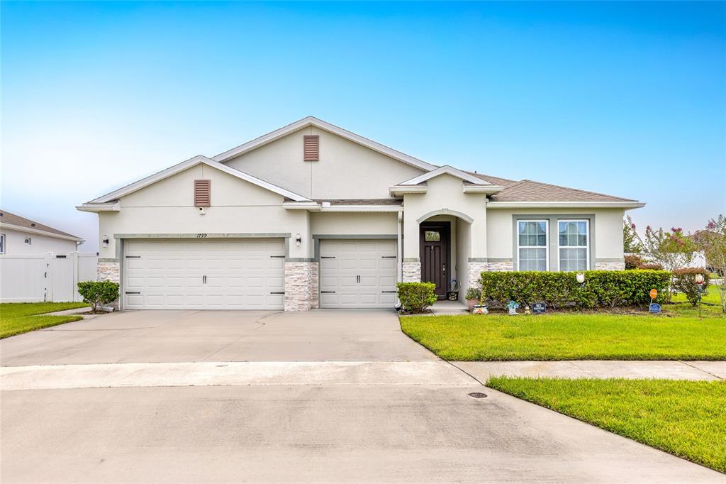 A single-story house with a three-car garage, stucco exterior, and a front lawn — 1799 RANGER HIGHLANDS ROAD, KISSIMMEE, FL