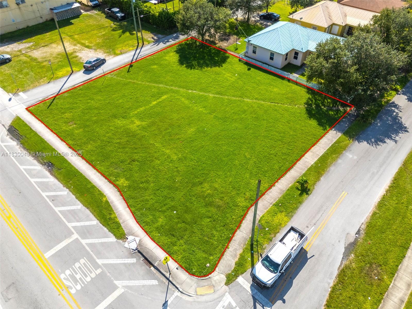 An aerial view shows a vacant, grass-covered corner lot outlined in red — 604 SW 6th Ave, Homestead FL 33030, HOMESTEAD, FL
