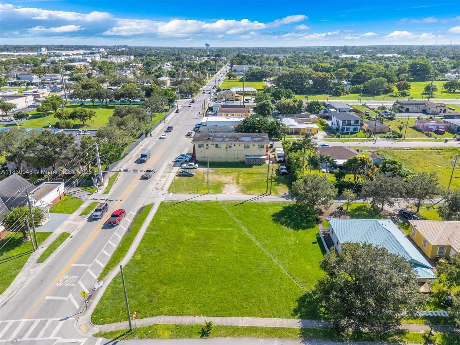 An aerial view shows a vacant grassy lot next to a road and residential buildings — 604 SW 6th Ave, Homestead FL 33030, HOMESTEAD, FL