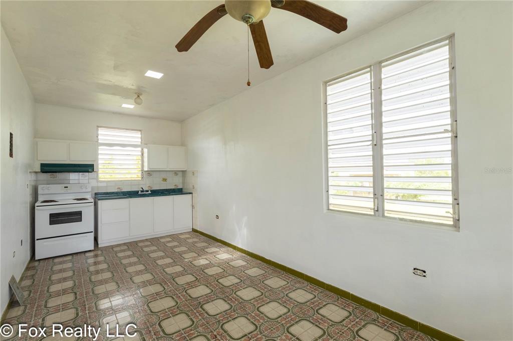 A kitchen with white cabinets, a white stove, and patterned tile flooring — Solar B AVENIDA MARIA BETTEGA, AGUADILLA, PR