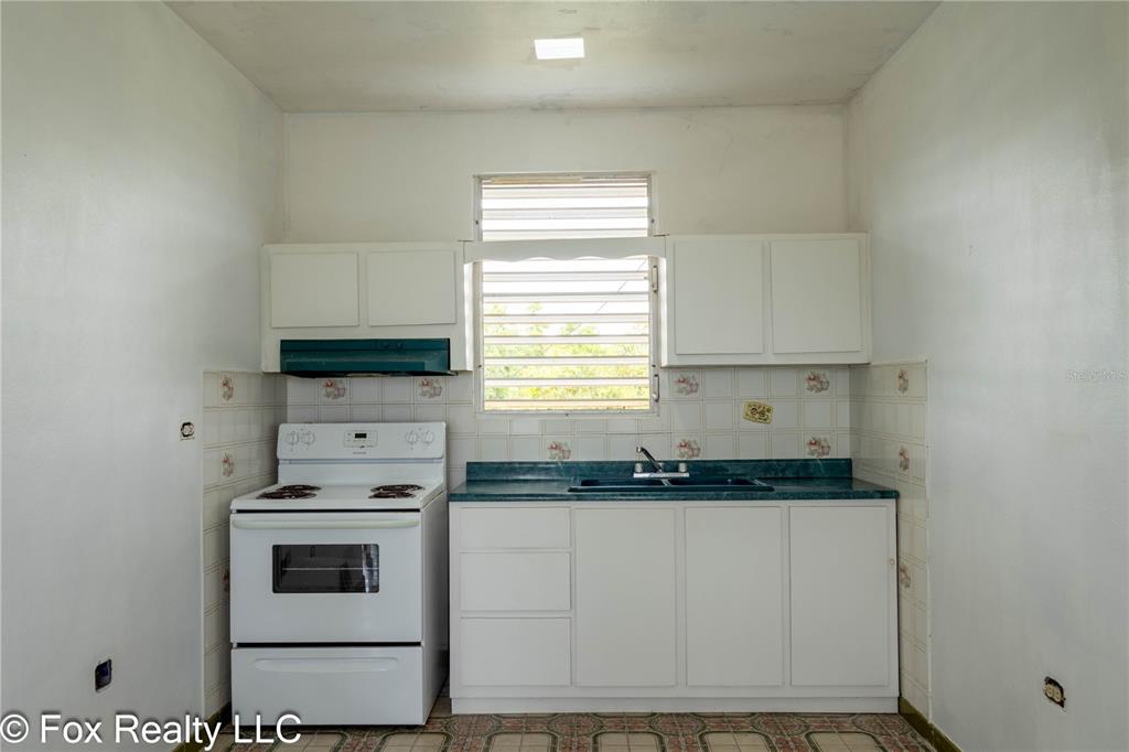 A kitchen features white cabinets, a white stove, a green countertop, and a window — Solar B AVENIDA MARIA BETTEGA, AGUADILLA, PR