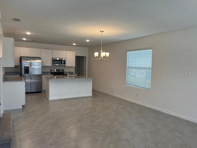 A kitchen with white cabinets, stainless steel appliances, and an island opens to a dining area — 642 BELGROVE STREET, DEBARY, FL