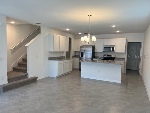 A kitchen with white cabinets, stainless steel appliances, and an island overlooks a staircase — 642 BELGROVE STREET, DEBARY, FL